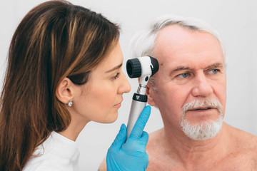 Doctor examining patient skin moles with dermoscope