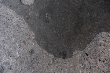 Concrete sidewalk embedded with stones texture with big black patch and markings - Blank stone patch wall background with brick and pebbles and dark splat pattern