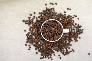 Coffee beans covered in a white Cup and scattered next to the linen fabric