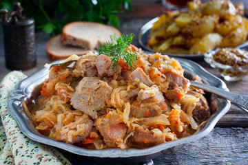 Braised cabbage with turkey thigh meat on a wooden table, horizontal