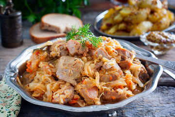 Braised cabbage with turkey thigh meat on a wooden table, horizontal