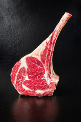 Raw dry aged wagyu tomahawk steak on black background with copy space