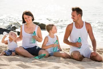 family drinking water on the beach.
