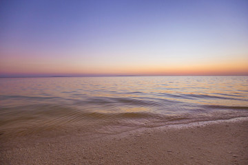 calm sea water beach with white sand, in a tranquil colorful summer sunset dusk background photo
