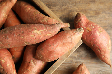 Wooden crate with sweet potatoes on table, top view