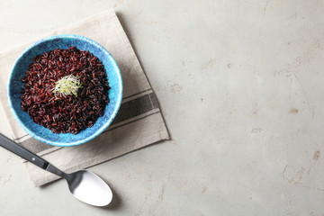 Bowl of boiled brown rice and spoon on table, flat lay. Space for text