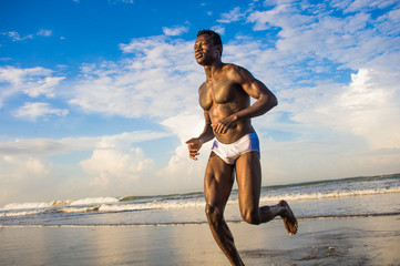 happy and attractive black afro American man with fit healthy and muscular body running on beach...