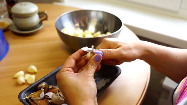 Cleaning garlic with a knife.