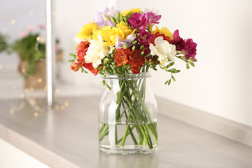 Beautiful spring bright freesia flowers in vase on table