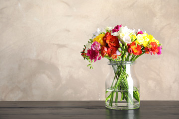 Bouquet of spring freesia flowers in vase on table. Space for text
