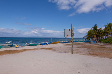  a simple cement basketball field at the white sand beach with fisher boats, a rural simple life scene
