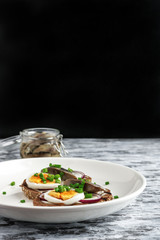 sandwiches with herring boiling eggs chopped green onions on white plate vertical orientation