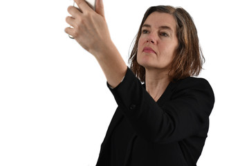 Attractive middle-aged woman with half-long graying hair makes a selfie with her phone. White background.