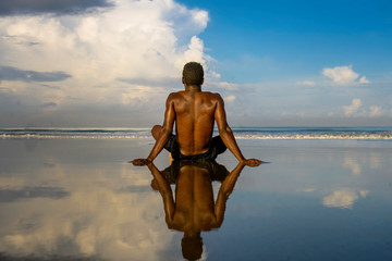 young attractive and relaxed black afro American man with fit body and muscular back sitting on beach sand enjoying beautiful view thinking and meditating free