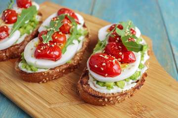 Fototapeta na wymiar homemade sandwiches with avocado boiling egg cream cheese cherry tomatoes sesame seeds on cutting board