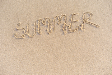 The word summer on the sand written by hand