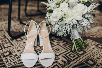 white shoes of the bride stand next to the wedding bouquet