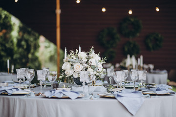 banquet table is decorated with plates, cutlery, glasses, candles and flower arrangements