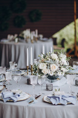 banquet table is decorated with plates, cutlery, glasses, candles and flower arrangements