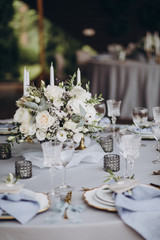 banquet table is decorated with plates, cutlery, glasses, candles and flower arrangements