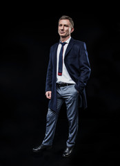 elegant fashionable man in a shirt and coat on standing on a black background