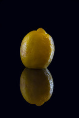 Yellow lemon with reflection on black background
