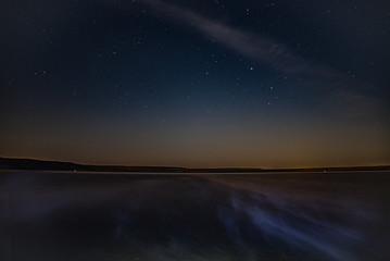 The fog creeps over the lake at night