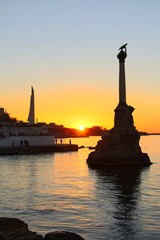 Embankment in the center of Sevastopol during sunset. In the rays of the setting sun, the Monument to the Sunken Ships and Monument to the Bayonet and Sail are visible.