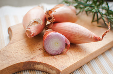 Close-up of shallots with fresh rosemary on cutting board