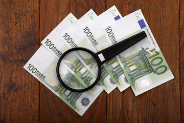 Euro is lying on the table under a magnifying glass.