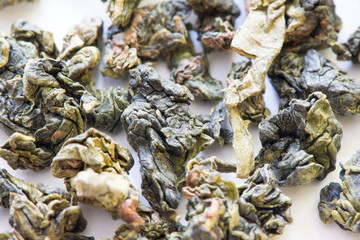 Green leaf tea versus black one in Yin Yang shaped plate, isolated on white