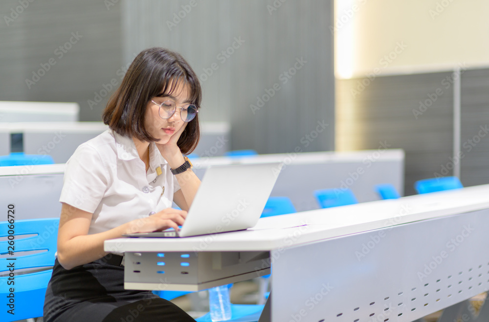 Wall mural girl with glasses look at laptop while doing homework