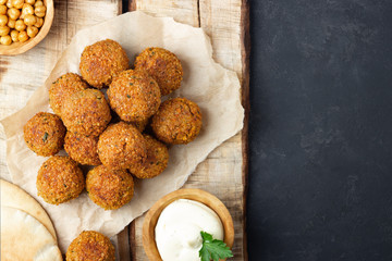Vegetarian chickpeas falafel balls on wooden rustic board. Traditional Middle Eastern and arabian food. Dark background. Copy space.