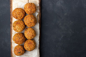 Vegetarian chickpeas falafel balls on wooden rustic board. Traditional Middle Eastern and arabian food. Dark background. Copy space.