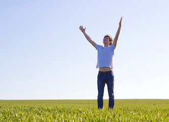 boy teenager walking on a field covered with green shoots of wheat