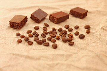 Chocolate cubes with coffee beans on a linen texture background.