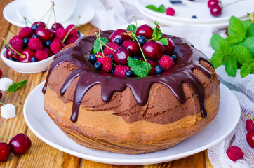Marble cream cake with chocolate glaze, fresh berries, whipped cream and mint.