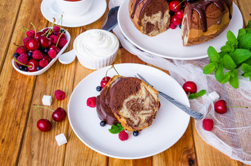 Marble cream cake with chocolate glaze, fresh berries, whipped cream and mint.