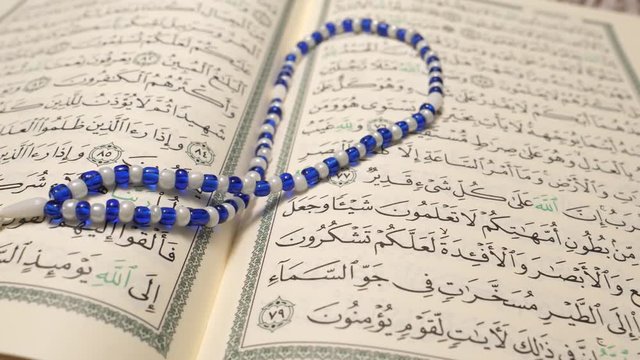 Closeup up shot of the holly Quran pages with some praying beads.