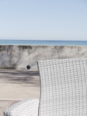 Rückenlehne eines weißen Korbstuhls an der Küste