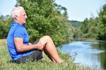 Naklejka na ściany i meble Stressed Athletic Male Senior Sitting By River