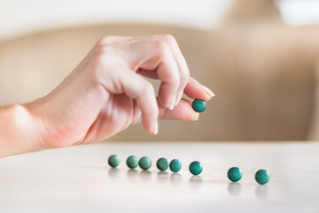 Obraz na płótnie Canvas Female hand holding a spirulina pill next to pills on a table.