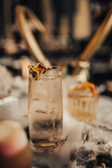 A close up shot of whisky cocktails with ice cubes and dry ice. Concept of fine alcohol, beverage and mixed cocktails. Luxurious lifestyle. Selective focus on the cocktails.