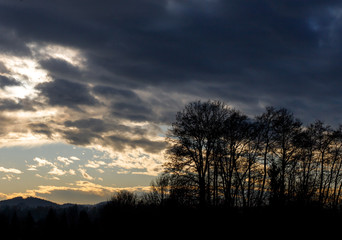colorful sunset with hills, clouds and trees