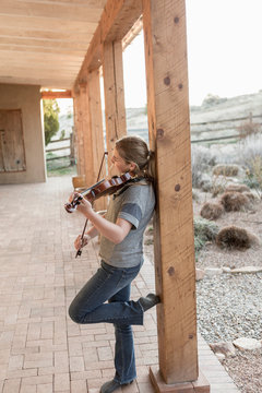 12 Year Old Girl Playing Violin Under Portal In Rural Setting