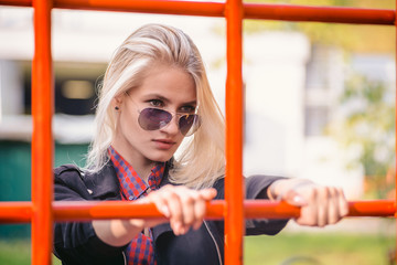 Obraz premium Cool girl in sunglasses looking through the net on the Playground in the Park for a walk.