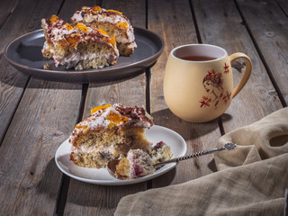 Homemade cake cut into pieces on plates and a large ceramic mug of tea