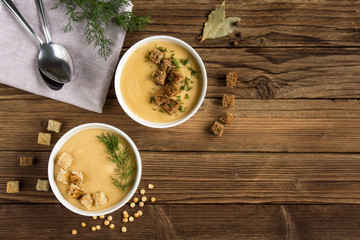 pea soup with croutons and greens on a wooden background