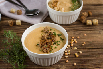 pea soup with croutons and greens on a wooden background