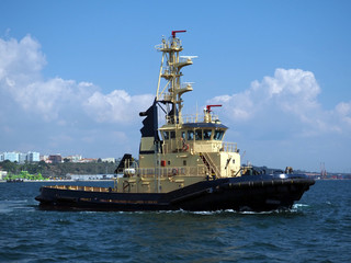 Coastal tugboat underway to towage assistance operations within port boundries.